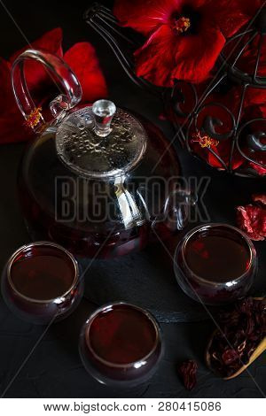 Herbal Hibiscus Tea Carcade With Red Hibiscus Flowers. Dark Mood Photo.