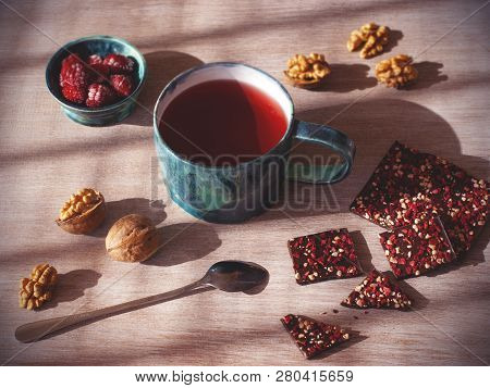 Hot Tea And Homemade Chocolate With Nuts And Raspberries On Wood Background, Slightly Top View