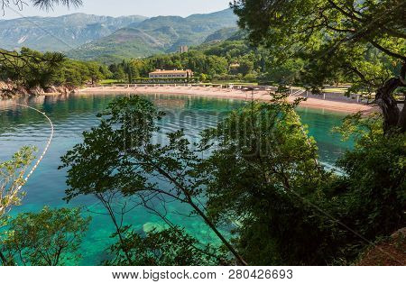 Pink Sandy Milocher Beach Through Branches Of Trees  (montenegro, Budva)