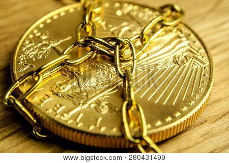 Closeup Of Golden Coin In Golden Chains Laying On Wooden Background