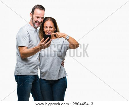 Middle age hispanic couple texting message on smartphone ver isolated background very happy pointing with hand and finger