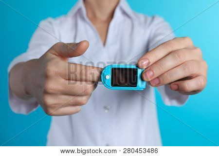 Female Doctor Holding Pulsimeter On Color Background, Closeup. Medical Object