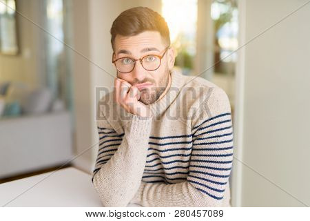 Young handsome man wearing glasses at home thinking looking tired and bored with depression problems with crossed arms.