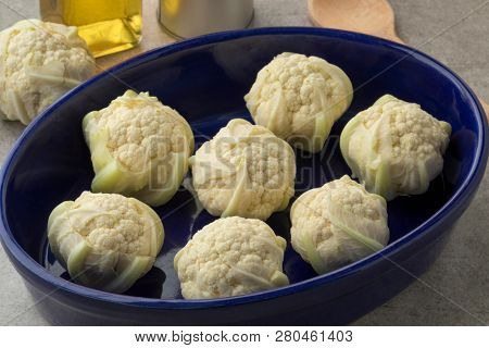 Mini cauliflowers in a blue dish ready to cook in the oven