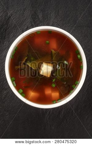 A Photo Of A Bowl Of Miso Shiru Soup With Tofu, Scallions, And Wakame Seaweed, Shot From The Top On 