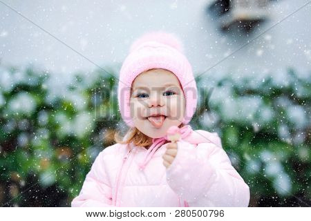 Portrait Of Little Toddler Girl Walking Outdoors In Winter. Cute Toddler Eating Sweet Lollypop Candy