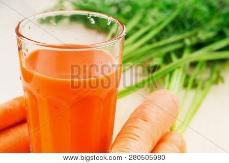 Fresh Carrot Juice In Glass On Wooden Table Background.