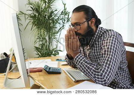 Young Programmer With His Hands Put Together By Face Looking At Data On Computer Screen While Trying