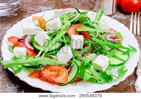 Fresh  Green Salad With Cucumber, Arugula,  Soft Cheese And Crackers On A Dark Table. Healthy Food L