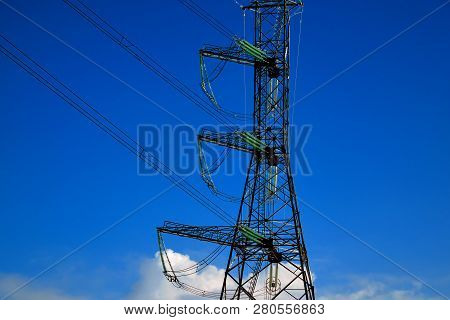 A Transmission Tower Or Electricity Pylon With Blue Sky. It Is A Tall Structure, Usually A Steel Lat