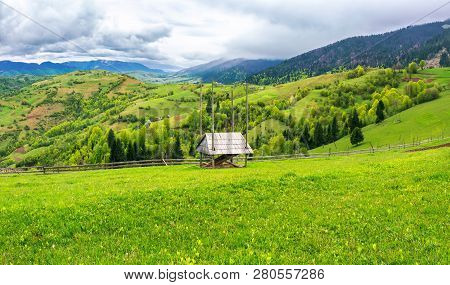 Hay Shed On A Grassy Field In Mountains. Beautiful Countryside Landscape In Springtime. Cloudy Foren