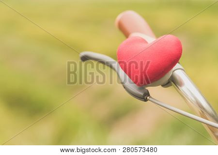 A Little Red Heart Pillow On The Bicycle Handlebar.
