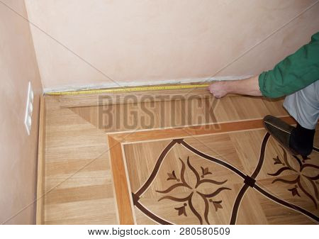 Wooden Batten Installation And Repair On Oak Wood Parquet. Contractor Hands Measuring Wooden Batten 
