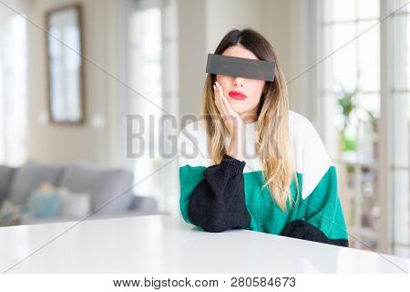 Young beautiful woman blindfold eyes with black censor band at home thinking looking tired and bored with depression problems with crossed arms.