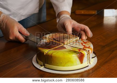Confectioner Cuts Dacquoise Cake In Mirrored Glaze. Modern Cooking. Woman Holds On Knife Piece Of Ca