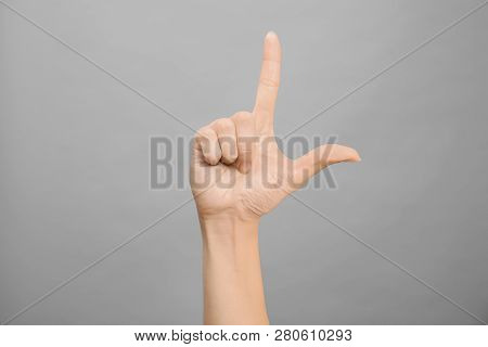 Woman Showing L Letter On Grey Background, Closeup. Sign Language