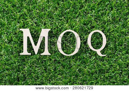 Wood Letter In Word Moq (abbreviation Of Minimum Order Quantity) On Artificial Green Grass Backgroun