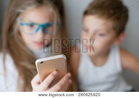 Two Little Kids Girl And Boy Using Mobile Phone Together
