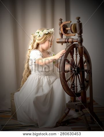A Cute Little Girl Wove A Wool With A Rotating Wheel. Retro Style, Memories Of The Past.
