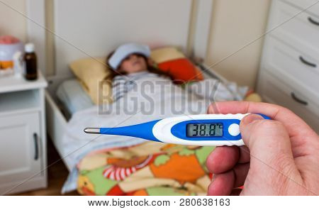 Close Up On A Digital Thermometer  That Marks 38 Degrees Celsius.  Little Girl Into Bed With Wet Clo