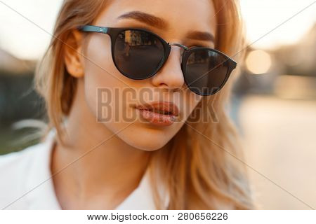 Portrait Of A Charming Young Woman With Sexy Lips In Black Stylish Sunglasses On Sunset Background.