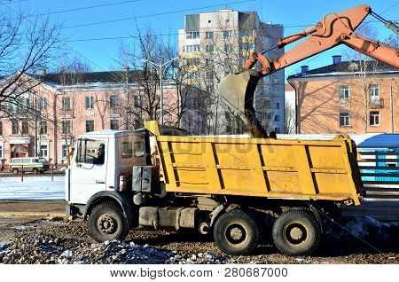 The Excavator Loads Crushed Stone In A Dump Truck Body. Iron Bucket Digging Machine.