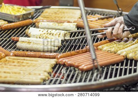 Gloved Hand Turns Barbecue Sausage In Pita Bread On The Grill