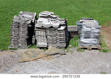 Used Grey Old Concrete Roof Tiles Put On One Pile On Wooden Pallets After Removing From Abandoned Ho