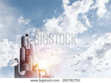 Young Female Doctor With Folder In Hands Satnding On Stone Column