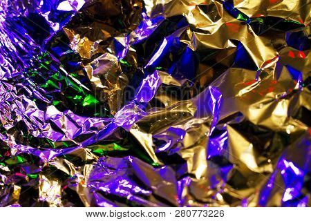 Silver Crampled Foil Background Lit With Colorful Lights. Texture Of Simple Metal Foil. Multicolored