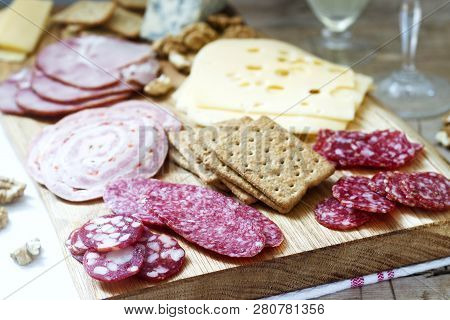 Appetizer Of Various Types Of Sausages, Meats, Cheeses And Crackers On A Wooden Board, Served To Win