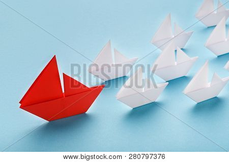 Opinion Leader, Influencer Concept. One Red Boat Leading Small White Ships On Blue Background