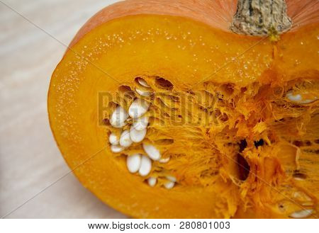 Half A Juicy Bright And Ripe Pumpkin In The Cut With A Stem And Seeds Of White. Pumpkin Oval-shaped 