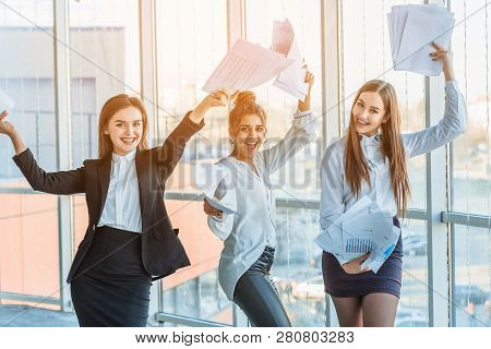 Three Young Beautiful Brunette Business Ladies In The Office. All Happy Dancing Dancing Up The Docum