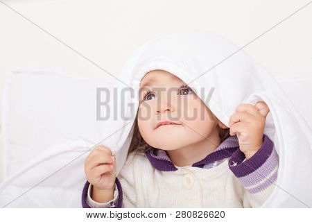 Portrait Of Baby Girl Lying In Bed Under Featherbed