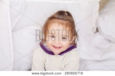Portrait Of Baby Girl Lying In Bed Under Featherbed