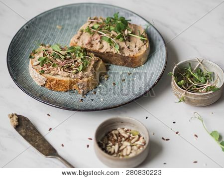 Two Toasts Duck With Prunes Rillettes Pate On White Bread With Sprouts And Various Seeds On A Blue P