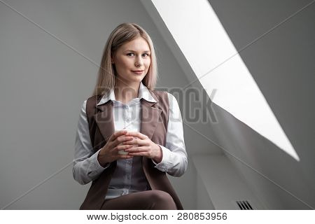 Blonde Girl In A Business Suit Works On A Computer In A White Bright Office.