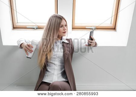 Blonde Girl In A Business Suit Works On A Computer In A White Bright Office.