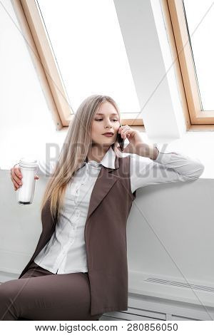 Blonde Girl In A Business Suit Works On A Computer In A White Bright Office.