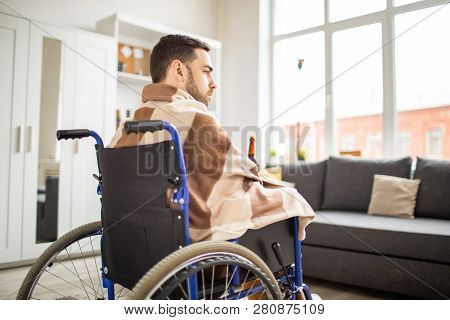 Young Unhappy Handicapped Man In Wheelchair Wrapped In Plaid Having Alcohol While Spending Time At H