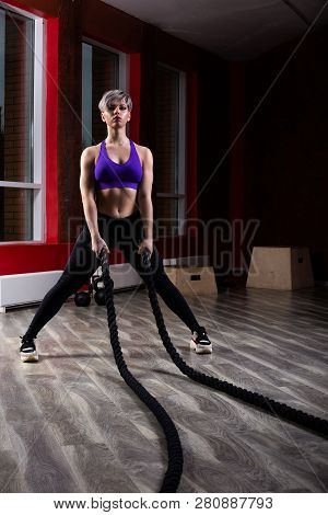 Fit And Muscular Woman Exercising With Battling Ropes At Fitness Studio. Female Athlete Doing Battle