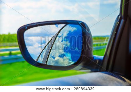 Blue Sky With Clouds In The Sideview Mirror Of A Car, On Road Countryside. Travel Natural Advanture 