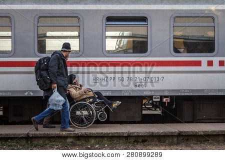 Sid, Serbia - November 14, 2015: Refugees, Men And A Woman In Wheelchair, Boarding A Train To Cross 