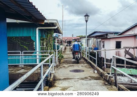 Labuan,malaysia-jan 15,2019:men Ride A Motorcycle In Wooden Houses Built On Stilts On Water In Patau