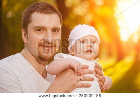 Baby with faher in the park in the rays of sunset. Toddler on the nature outdoors. Backlight. Summertime family  scene