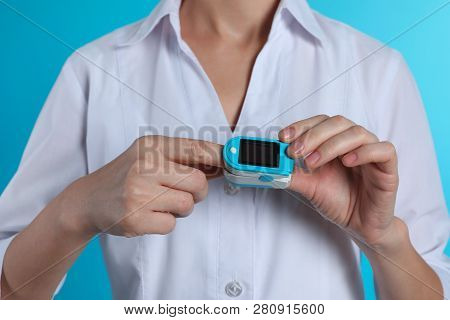Female Doctor Holding Pulsimeter On Color Background, Closeup. Medical Object