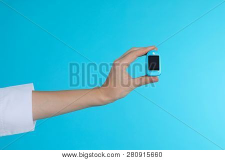 Female Doctor Holding Pulsimeter On Color Background, Closeup. Medical Object