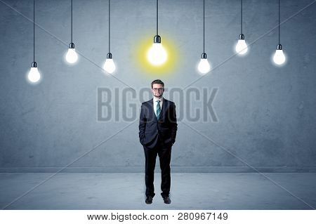 Handsome businessman in an empty space with bulbs above and uninspired face