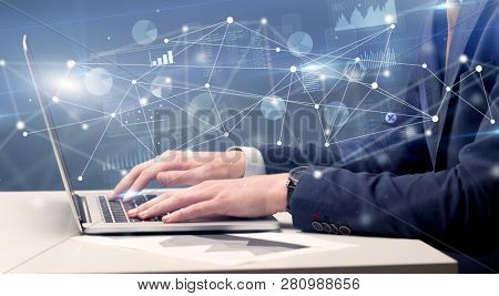 Businessman typing on laptop with linked reports charts grapghs around